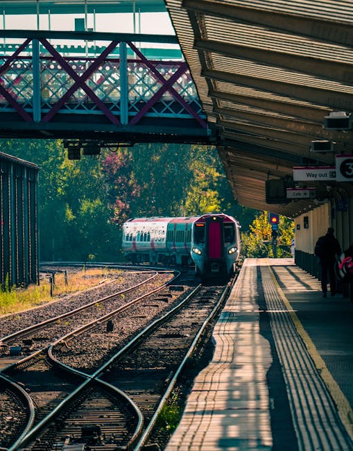 View of a modern train station platform near Barnes Bridge station SW13, featuring a covered canopy with white structural supports and translucent roofing panels. The concrete platform surface is clea